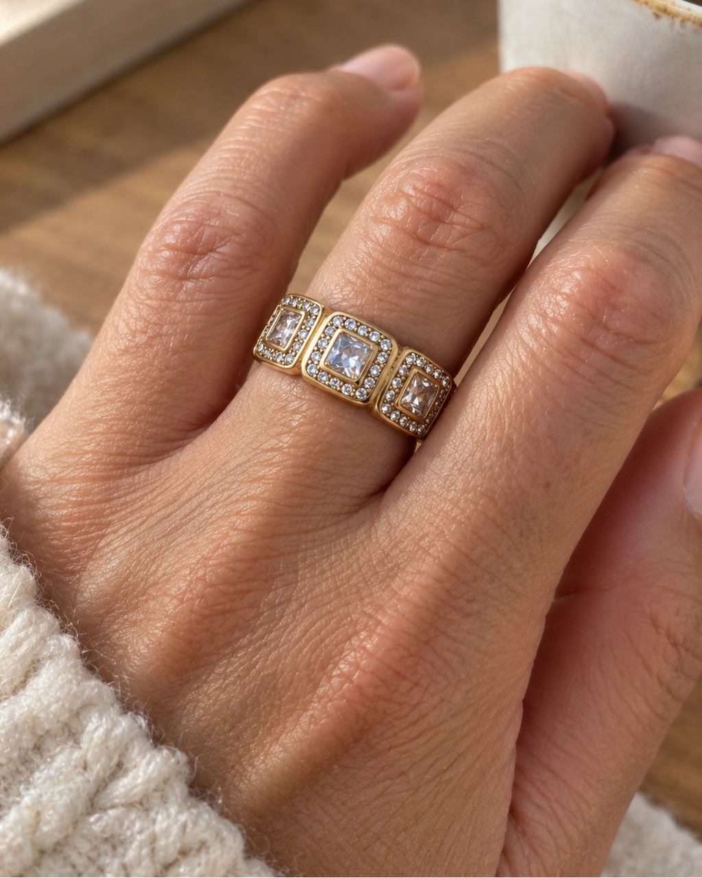 Bague Charleston pour femme en acier inoxydable doré PVD et zircons, portée à la main, au design géométrique inspiré de l’Art déco.