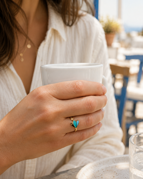 Photo de la bague dorée Elena en acier inoxydable, portée. on distingue la finesse des motifs et les nuances colorées vert et turquoise.