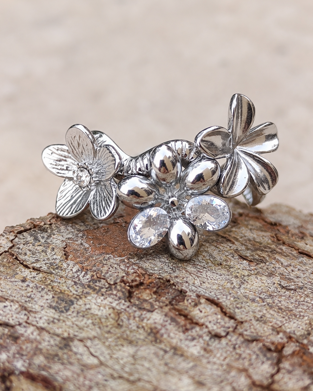 Bague fleur Un matin au jardin en acier inoxydable finition argentée, ornée de fleurs en relief et de deux zircons lumineux.