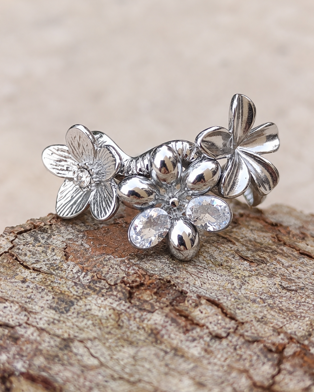 Bague fleur Un matin au jardin en acier inoxydable finition argentée, ornée de fleurs en relief et de deux zircons lumineux.