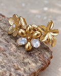 Bague fleur dorée Un matin au jardin en acier inoxydable finition PVD, ornée de fleurs en relief et de deux zircons, présentée en gros plan.