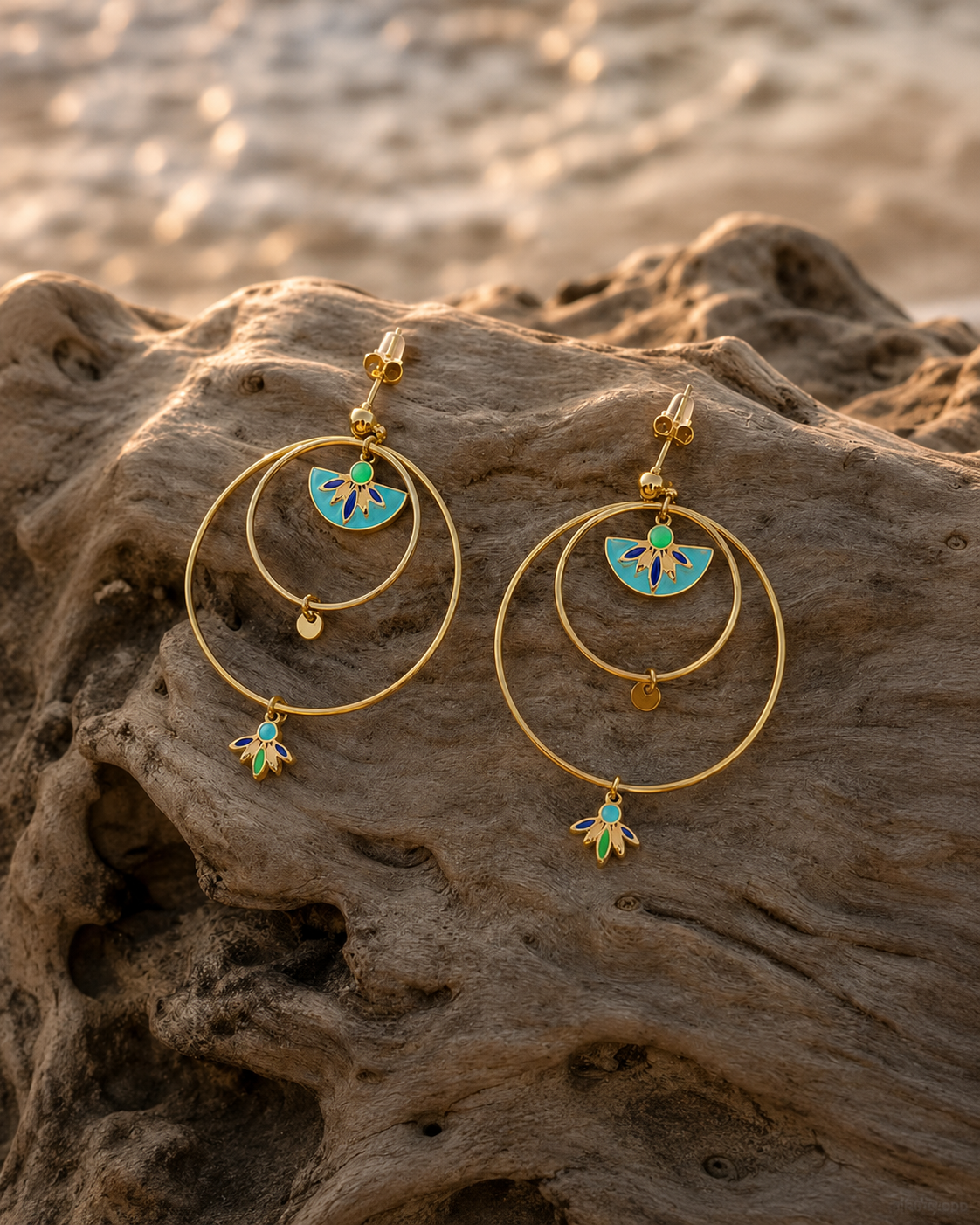 boucles d'oreilles créoles dorées Santorin en acier inoxydable posé sur un bois flotté.