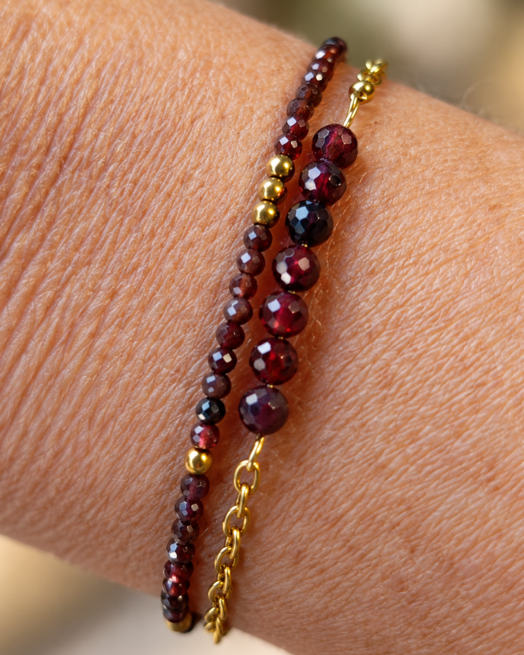 Gros plan du bracelet Garance porté au poignet, création artisanale française Yselia. Bracelet double rang composé de perles de grenat naturel facettées aux reflets rouge profond, de détails dorés et de finitions en plaqué or 18 carats. Bijou féminin élégant, créé et assemblé à la main en France.