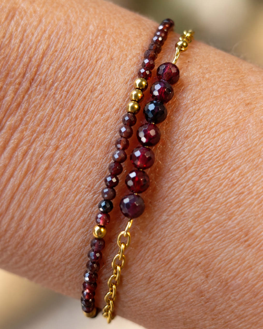 Gros plan du bracelet Garance porté au poignet, création artisanale française Yselia. Bracelet double rang composé de perles de grenat naturel facettées aux reflets rouge profond, de détails dorés et de finitions en plaqué or 18 carats. Bijou féminin élégant, créé et assemblé à la main en France.