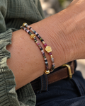 Bracelet femme double rang Jardin des Songes porté au poignet, en tourmalines naturelles multicolores avec perles et fleur en plaqué or 18 carats, bijou fait main en France.