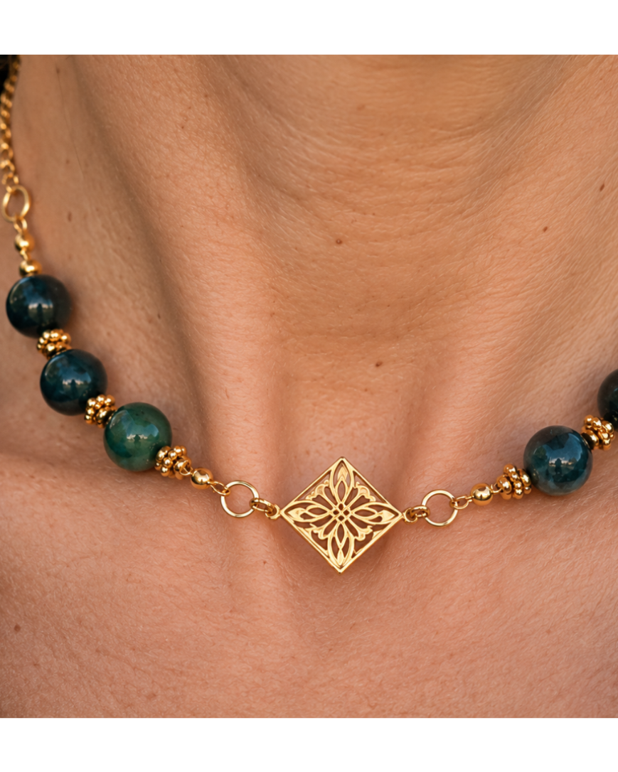 Gros plan sur le collier Arabesque Yselia, ses perles en agate verte naturelle aux nuances profondes, ses finitions dorées et son médaillon central ajouré à motif floral en plaqué or 18 carats. Création française.