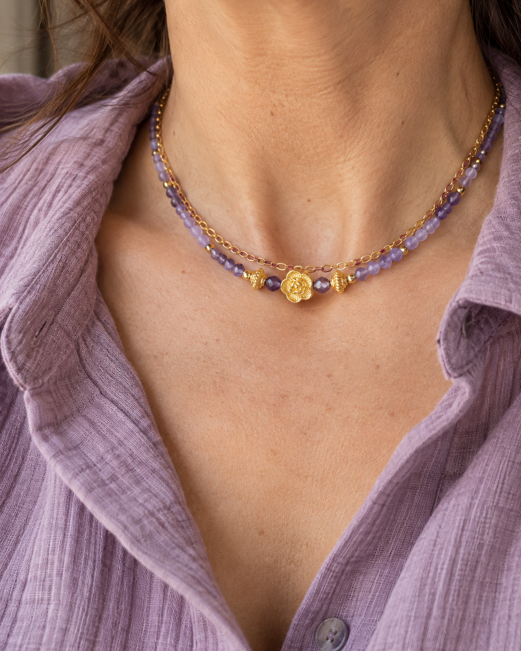 Collier femme Secret d’Améthyste porté au cou, composé de deux rangs: une chaine plaquée or 18 k et d' un rang de perles d’améthyste naturelle facettées et d’une petite fleur en plaqué or 18 carats. Bijou créé et assemblé en France.