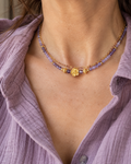 Collier femme Secret d’Améthyste porté au cou, composé de deux rangs: une chaine plaquée or 18 k et d' un rang de perles d’améthyste naturelle facettées et d’une petite fleur en plaqué or 18 carats. Bijou créé et assemblé en France.