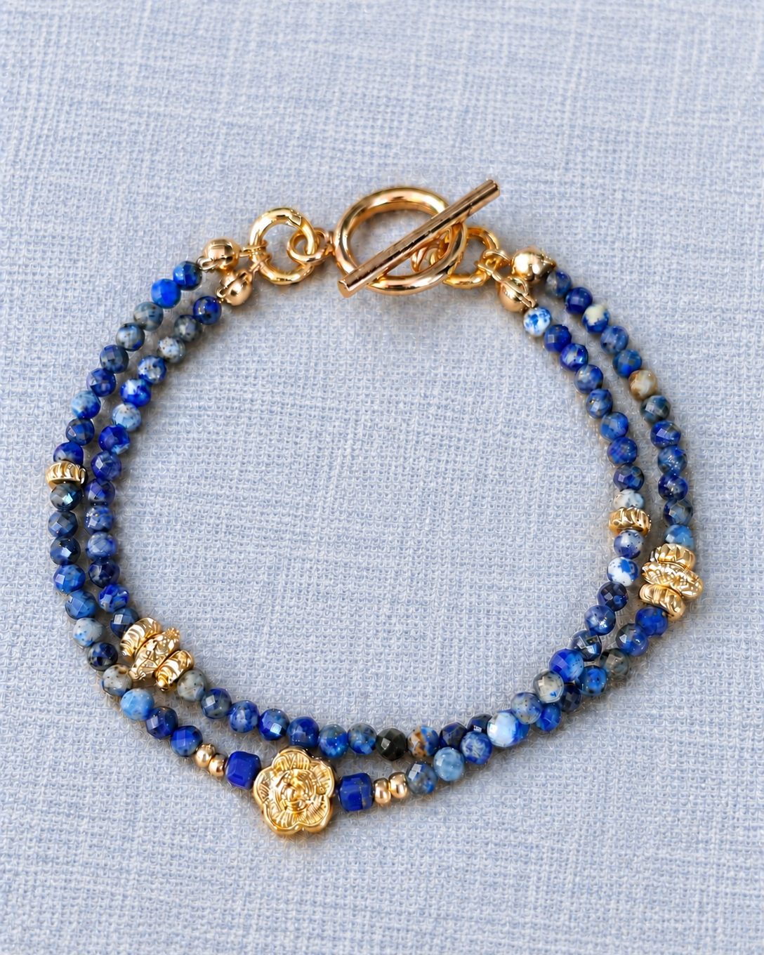 Bracelet double rang Songe d’une nuit d’été en lapis-lazuli naturel et plaqué or 18 carats, fait main en France sur fond en lin beige.