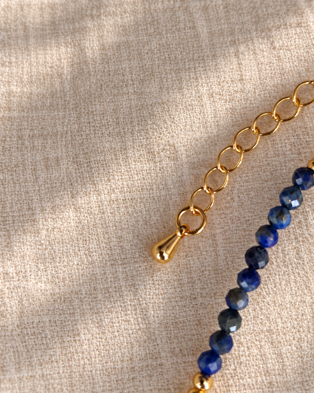 zoom sur la breloque en or 18 carats de la chainette d'extension du collier songe d'une nuit d'été en lapis lazuli et plaqué or 18 carats.