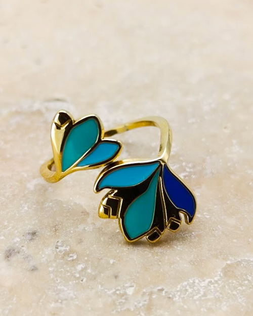 gros plan sur la bague dorée Melina de la collection Santorin. Bague en acier inoxydable avec des détails colorés vert bleu et turquoise.