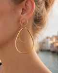 Grandes boucles d'oreilles Rialto en acier inoxydable doré, portée. Ces boucles d'oreilles pendantes et élégantes font partie de la collection Venezia de yselia bijoux