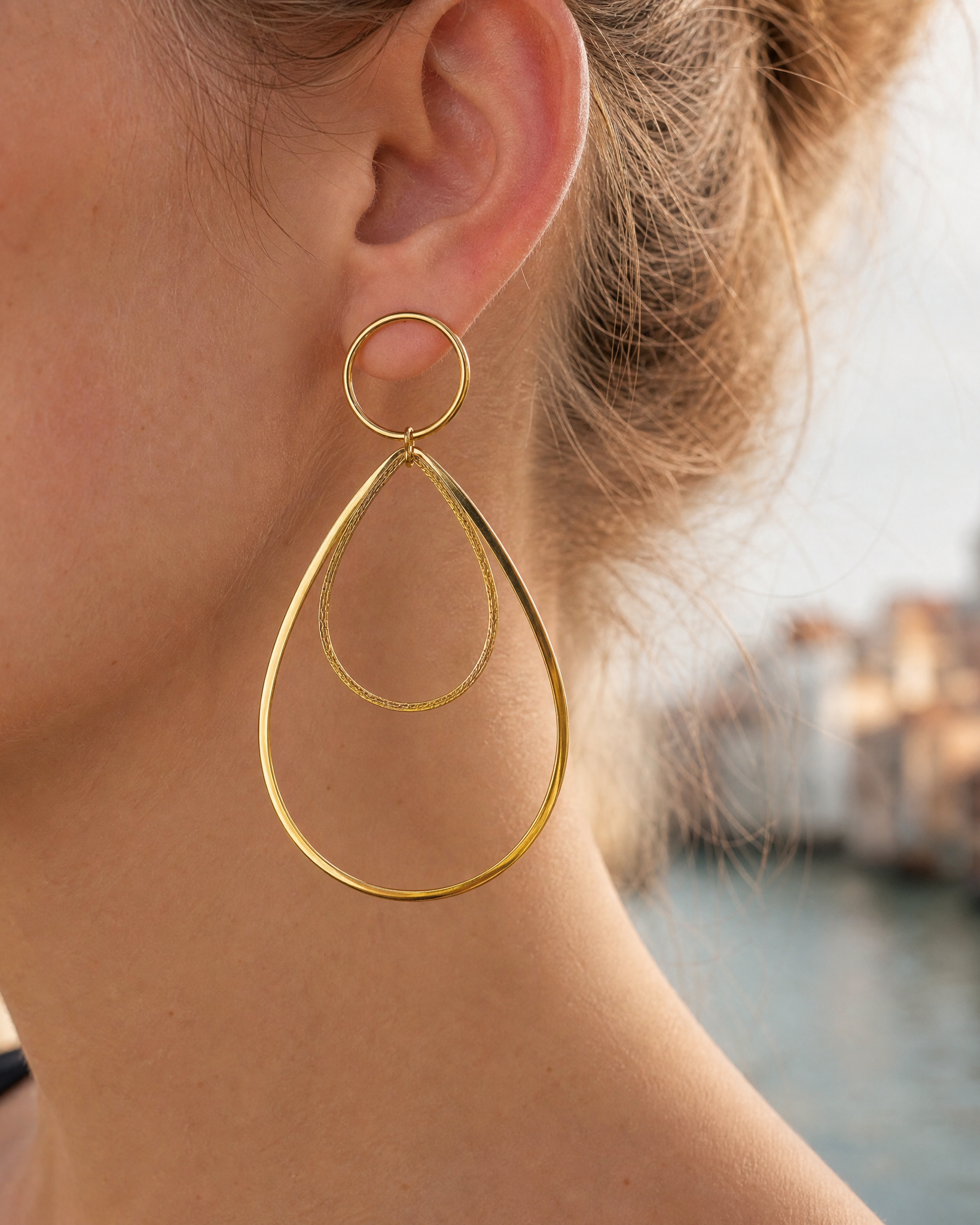 Grandes boucles d'oreilles Rialto en acier inoxydable doré, portée. Ces boucles d'oreilles pendantes et élégantes font partie de la collection Venezia de yselia bijoux