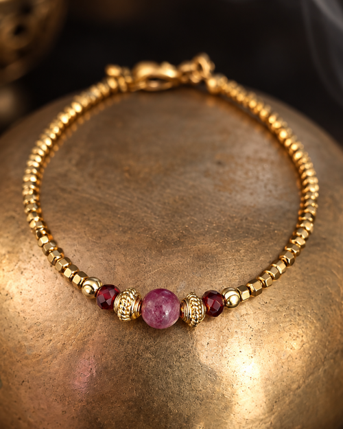 gros plan sur le bracelet Alma en hématites dorées, orné d'une spinelle rose, de 2 grenat et de perles finement travaillées en plaqué or 18k. Un bijou élégant fabriquer en France dans latelier d' Yselia