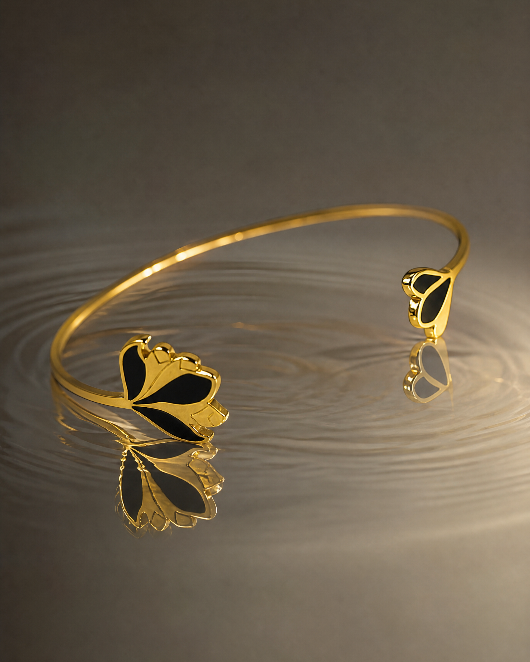 Gros plan sur les détails du bracelet Nymphéa laqué noir et doré en acier inoxydable. 