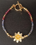 photo du bracelet Ondine en pierres naturelles composé de saphirs et de rubis, avec perles et fermoir en plaqué or 18k. Un médaillon en forme de nénuphar plaqué or 18k orne ce bracelet . fermoir à bascule