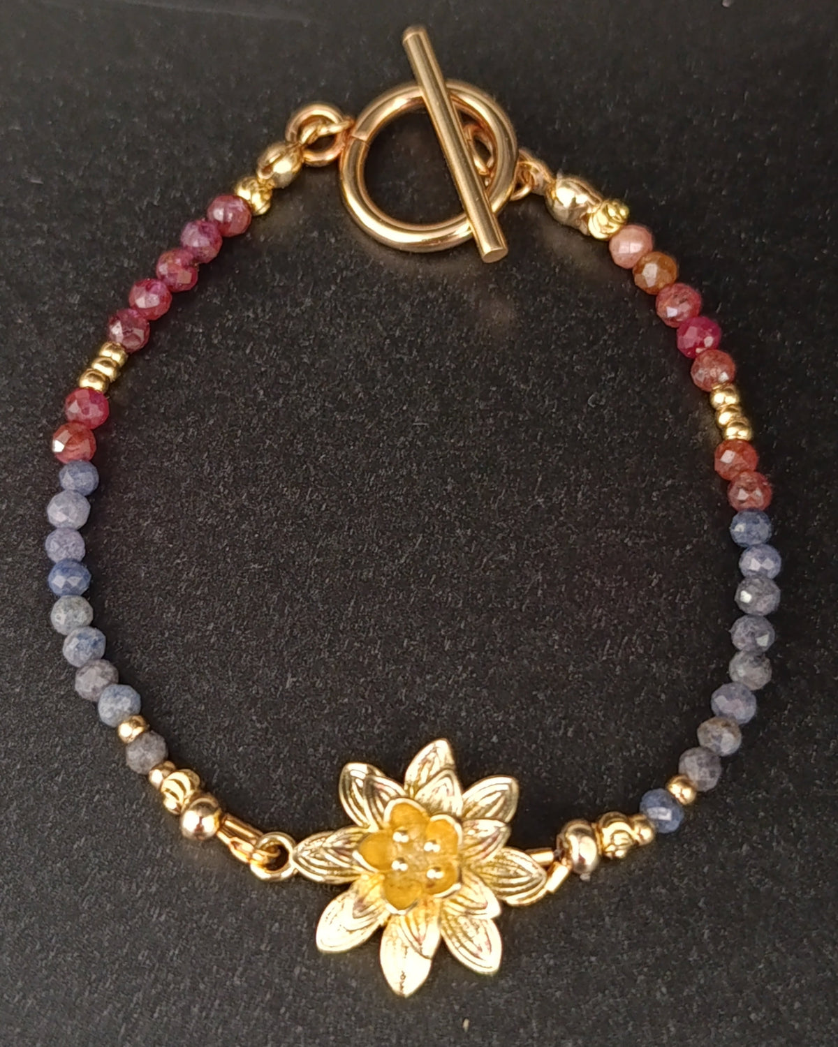 photo du bracelet Ondine en pierres naturelles composé de saphirs et de rubis, avec perles et fermoir en plaqué or 18k. Un médaillon en forme de nénuphar plaqué or 18k orne ce bracelet . fermoir à bascule