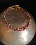 photo d bracelet double rang Isadora composé d'un rang de perles en rubis naturelles et d'un rang en hématites dorées , quelques perles travaillées en plaqué or 18 carats , de 2 grenat et une spinelle rose.