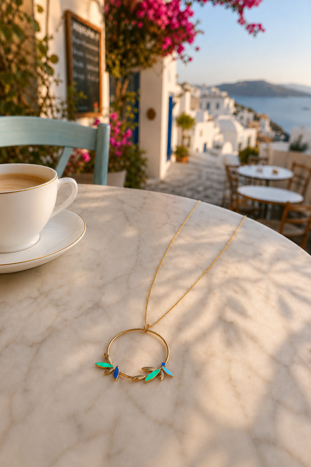 photo du pendentif du collier doré Santorin en acier inoxydable. le collier est posé et montre les touches de couleurs bleu vert et turquoise.