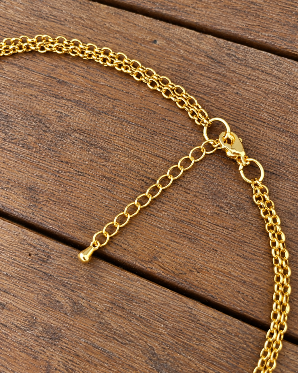 photo en gros plan du fermoir et de la chainette d'extension en forme de goutte du collier ras du cou arabesque grenat et agathe verte