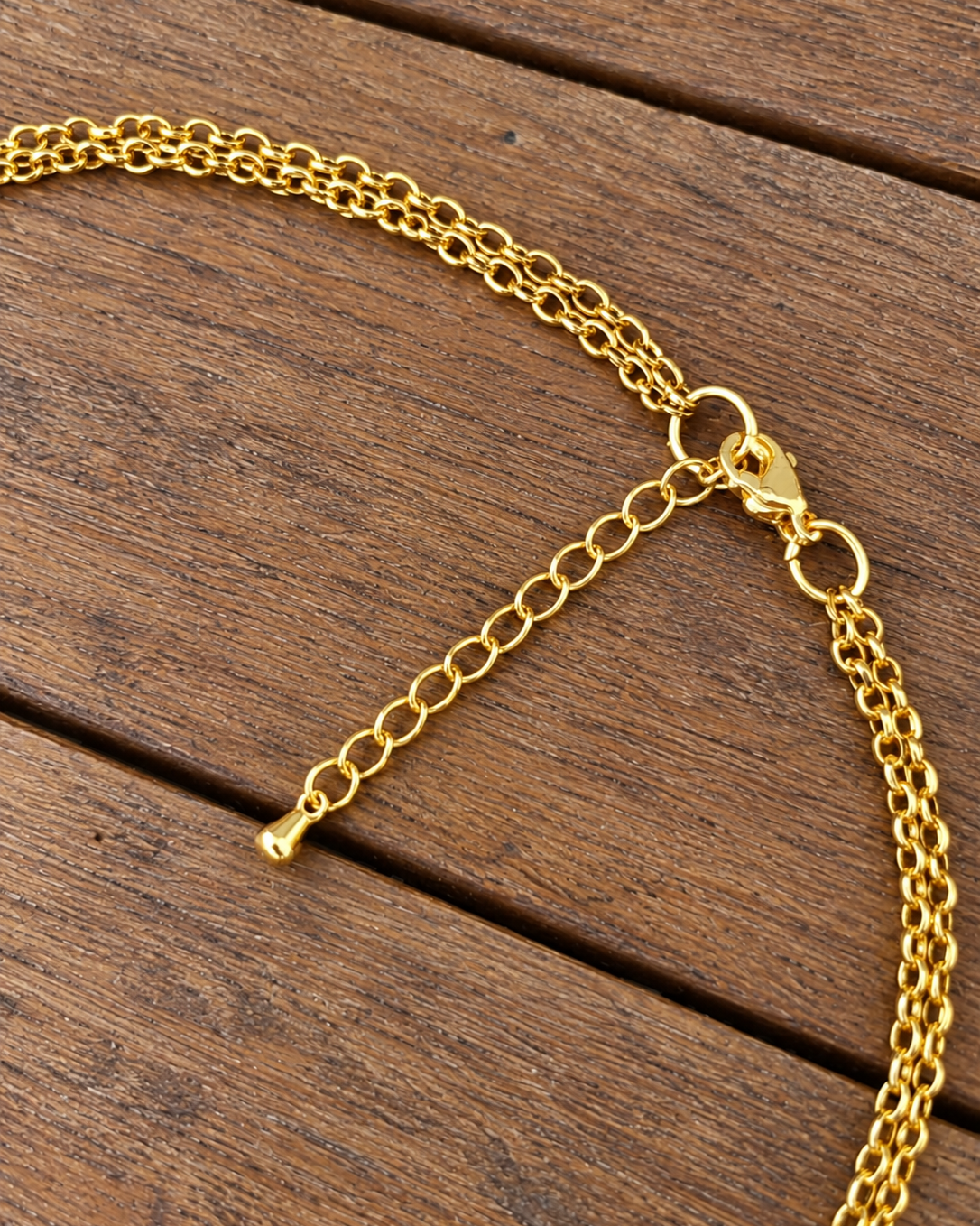 photo en gros plan du fermoir et de la chainette d'extension en forme de goutte du collier ras du cou arabesque grenat et agathe verte